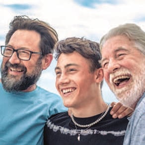Three smiling people standing closely together and laughing